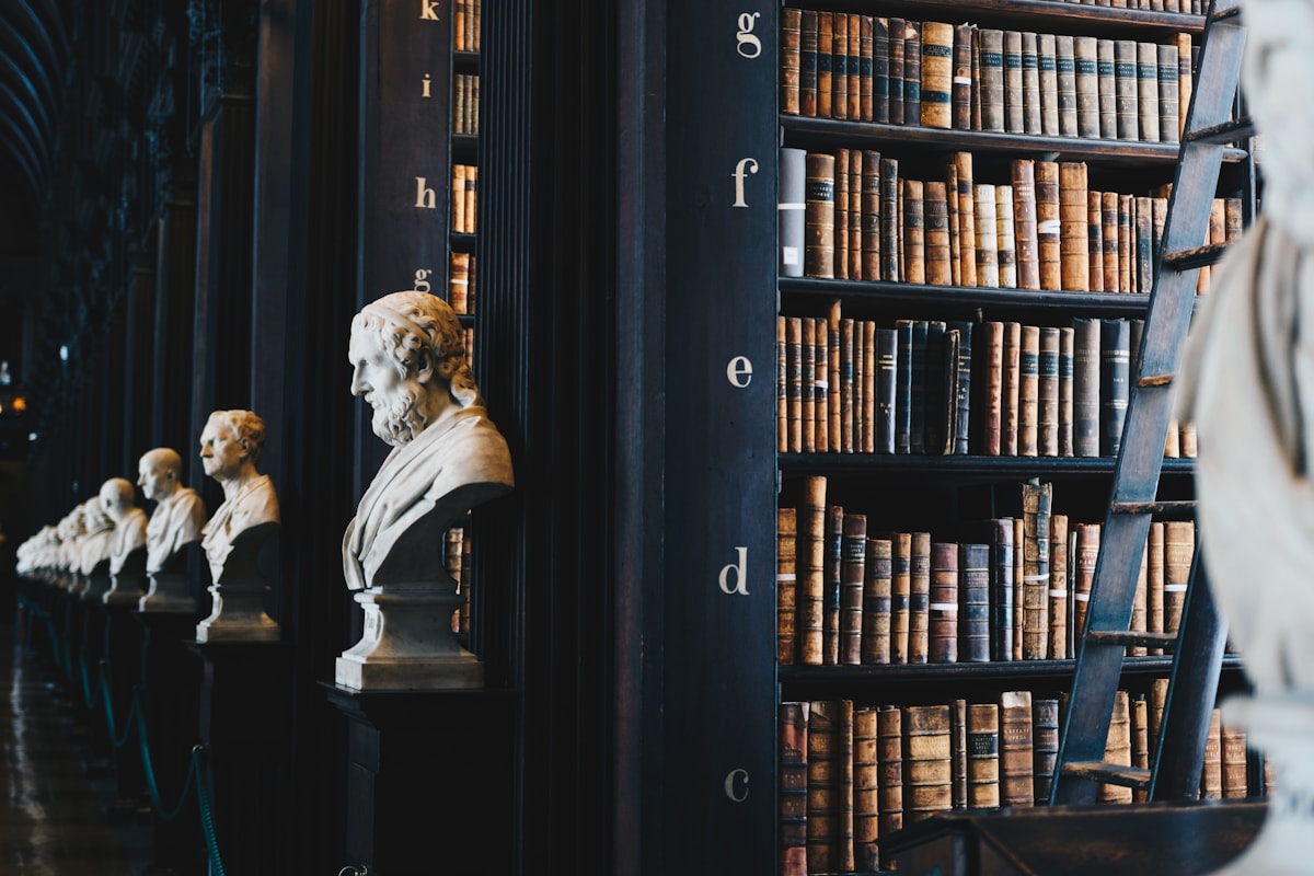 A walnut-paneled partner library at dusk, brass lamp lit, leather-bound volumes.